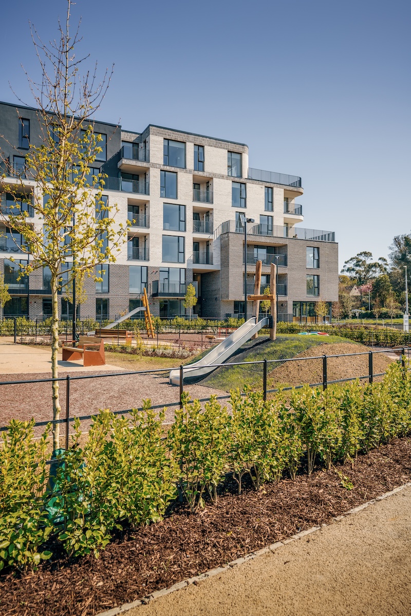 Brightly lit outside view of the Claremont residential development in Howth with playground in the foreground and a focus on the commercial windows and doors Ireland in the background.